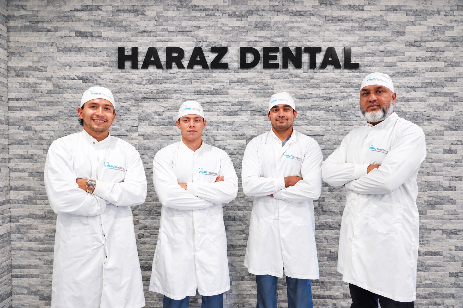 The Haraz Dental Group team in white coats standing in front of the Haraz Dental sign